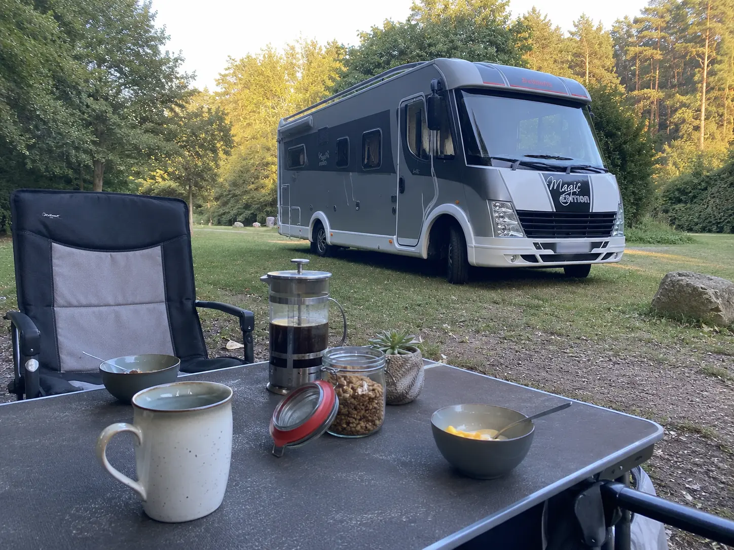 Husbil på en campingplats med kaffe och frukost på bordet